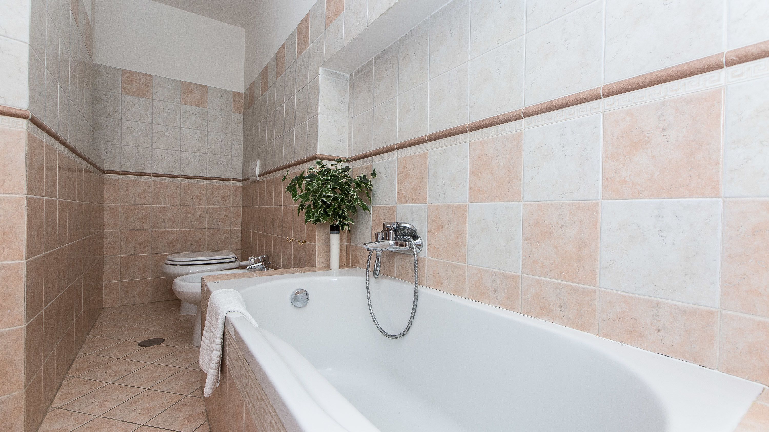 Et badeværelse med badekar, toilet og bruser.