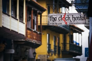 A sign for 'The Clock Hostel' with a rustic wooden design and a red decorative element. - The Clock Hostel And Suites (Cartagena)
