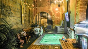 An indoor space with a wooden table, a green-lit square area, and a TV on a stand.