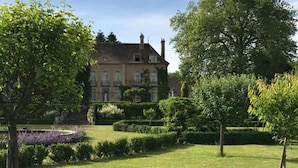 A large, historic building with a symmetrical facade, surrounded by well-manicured lawns and mature trees. - Château de Villette (Poil)