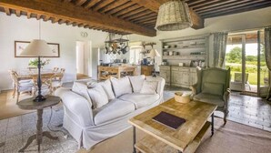 A cozy living room with a white sofa, wooden coffee table, and a dining area with a table and chairs. - Château de Villette (Poil)