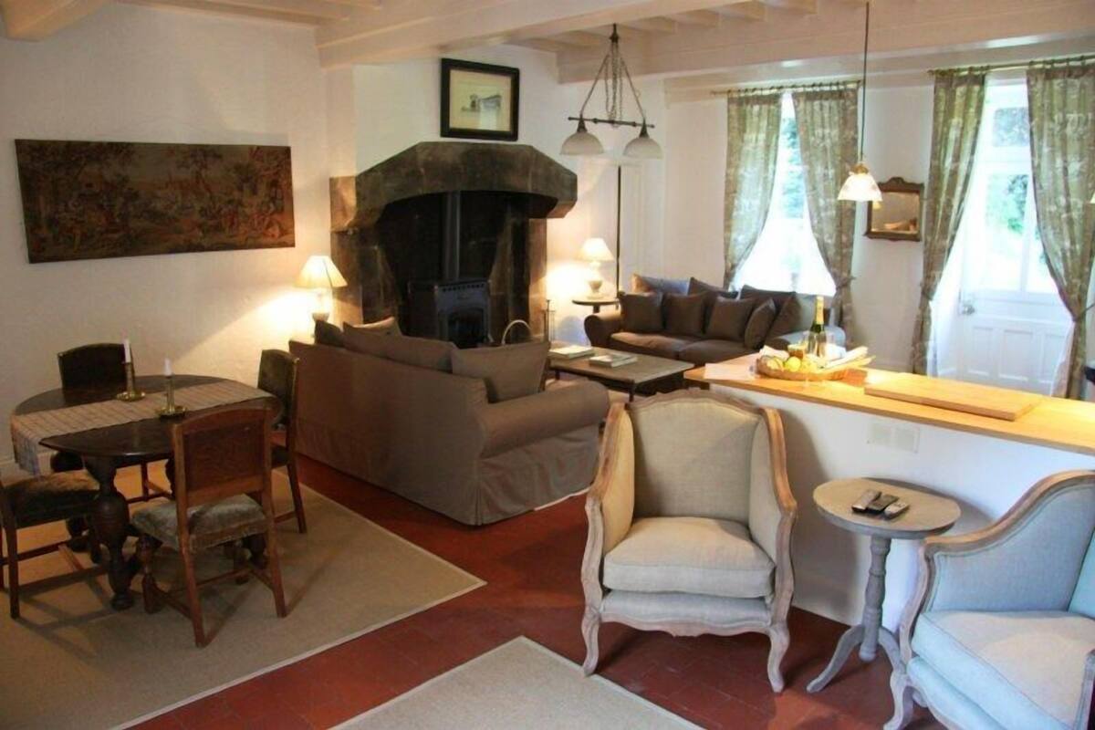 Una sala de estar acogedora con chimenea, un comedor con mesa y sillas, y una zona de estar con sofás y una mesita redonda.