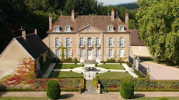 A large, symmetrical building with a central entrance, surrounded by well-manicured gardens and a clear sky. - Château de Villette (Poil)
