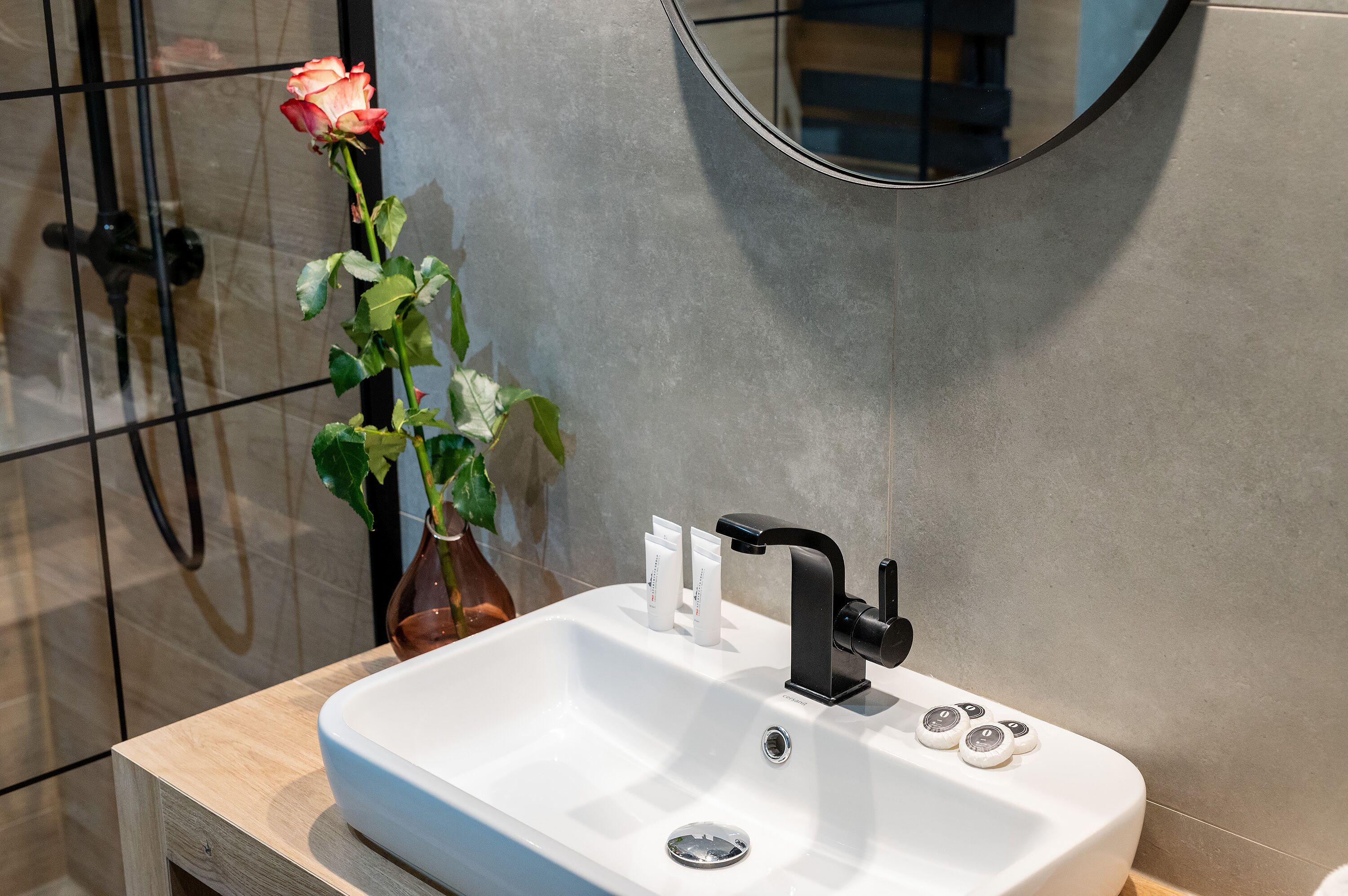 A modern bathroom with a white sink, black faucet, and a mirror above it.