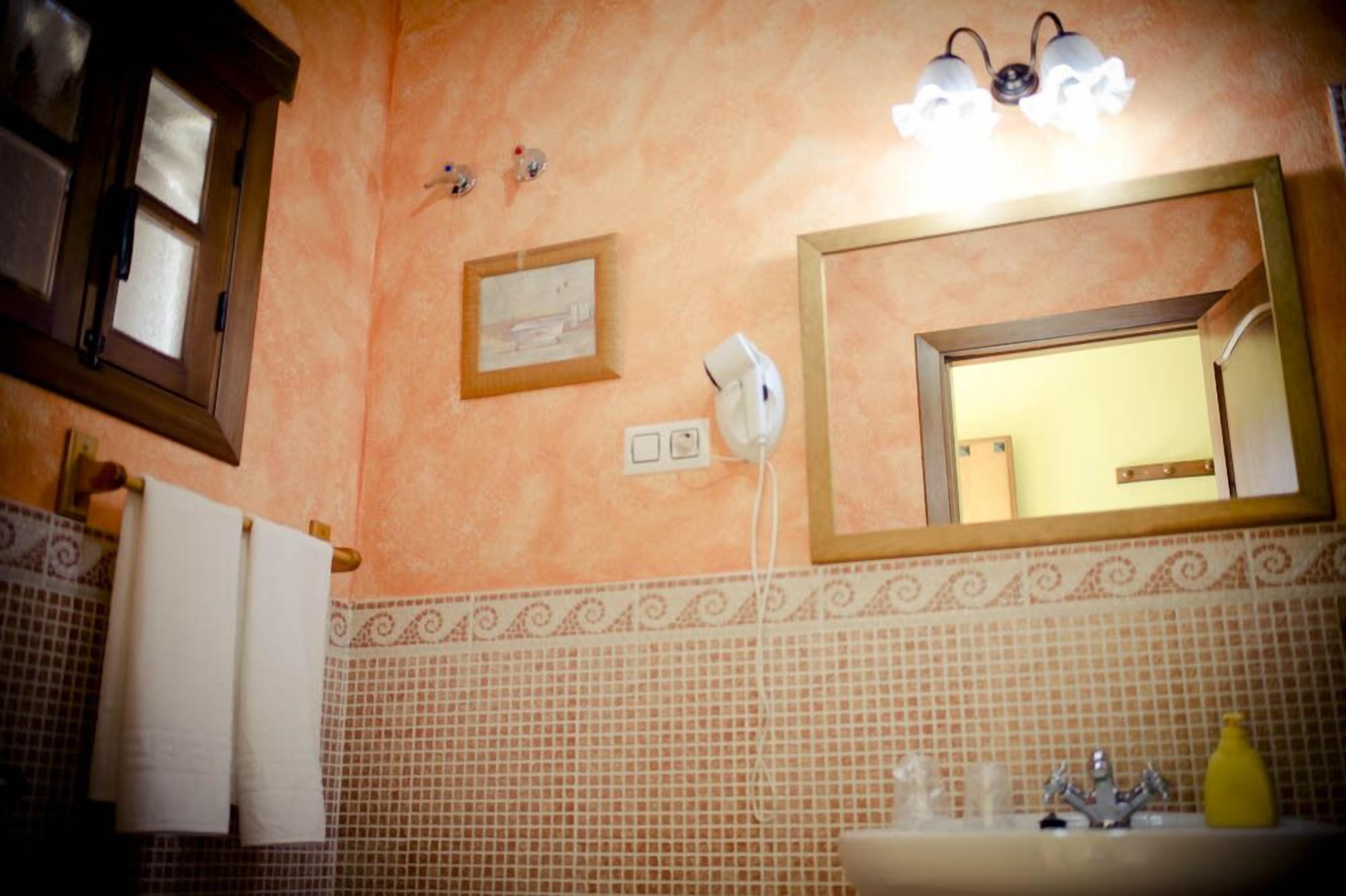 A bathroom with a tiled backsplash, a sink with a yellow soap dispenser, a mirror with a wooden frame, and a towel rack with a white towel.