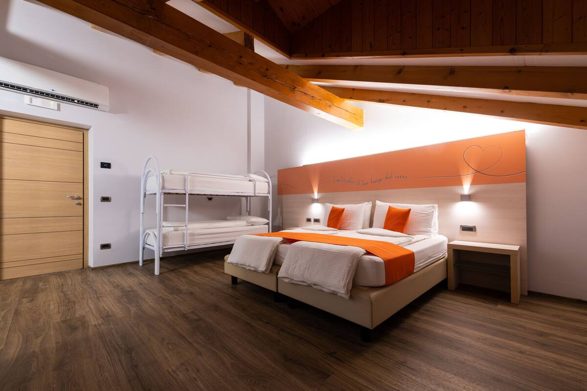 A bedroom with a bunk bed, a bedside table, a nightstand, and a wall-mounted light fixture.