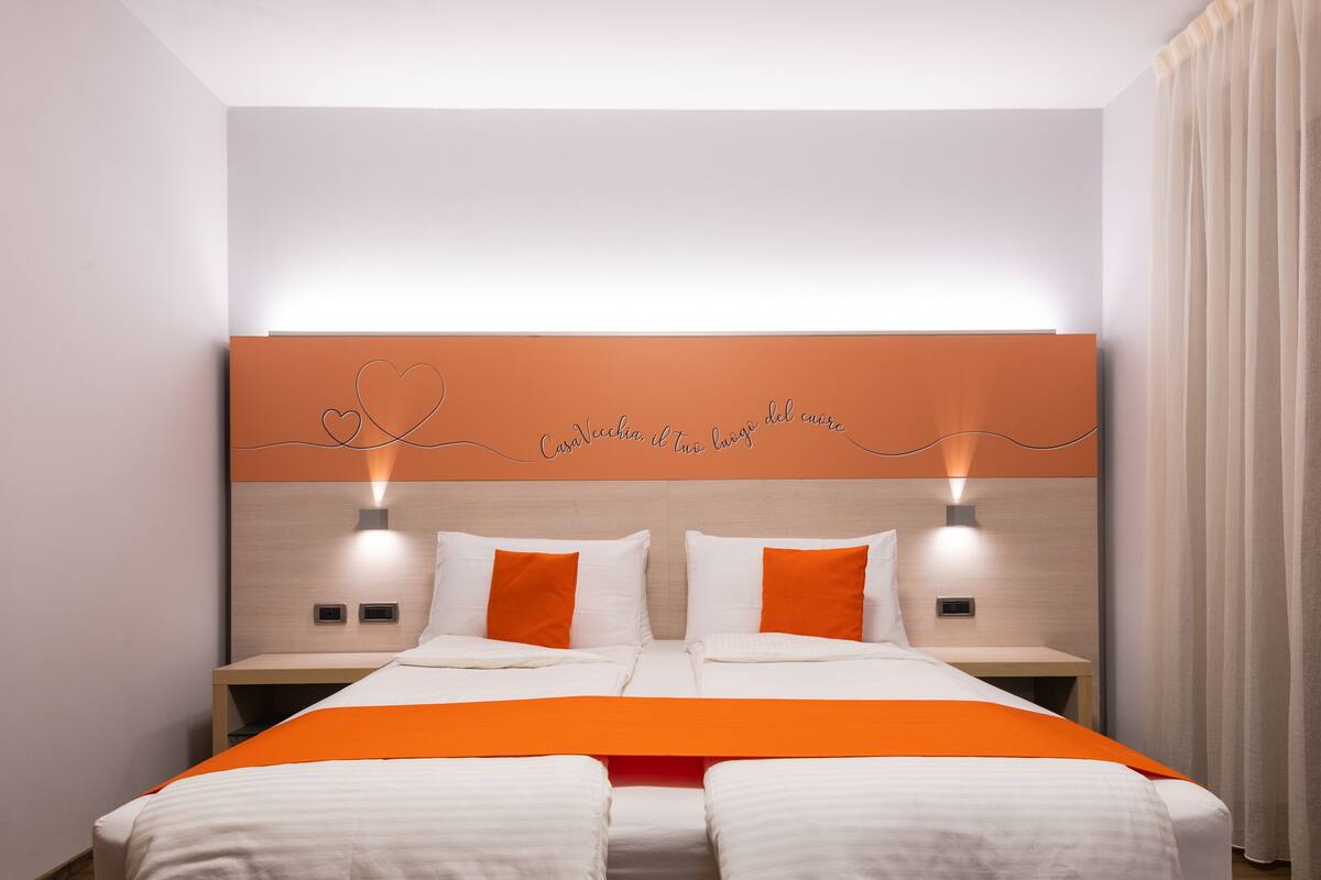 A hotel room with a bed, two bedside tables, and a headboard with a heart-shaped design.