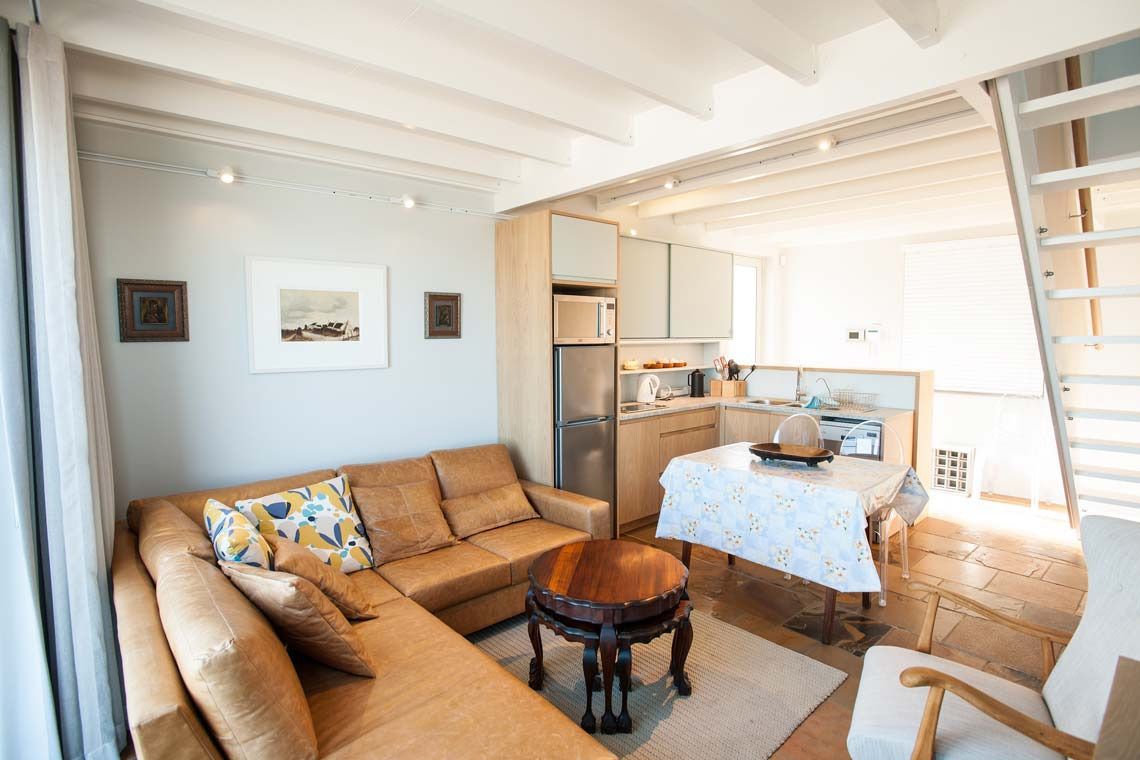 A modern living room with a sofa, a coffee table, and a dining area with a table and chairs.