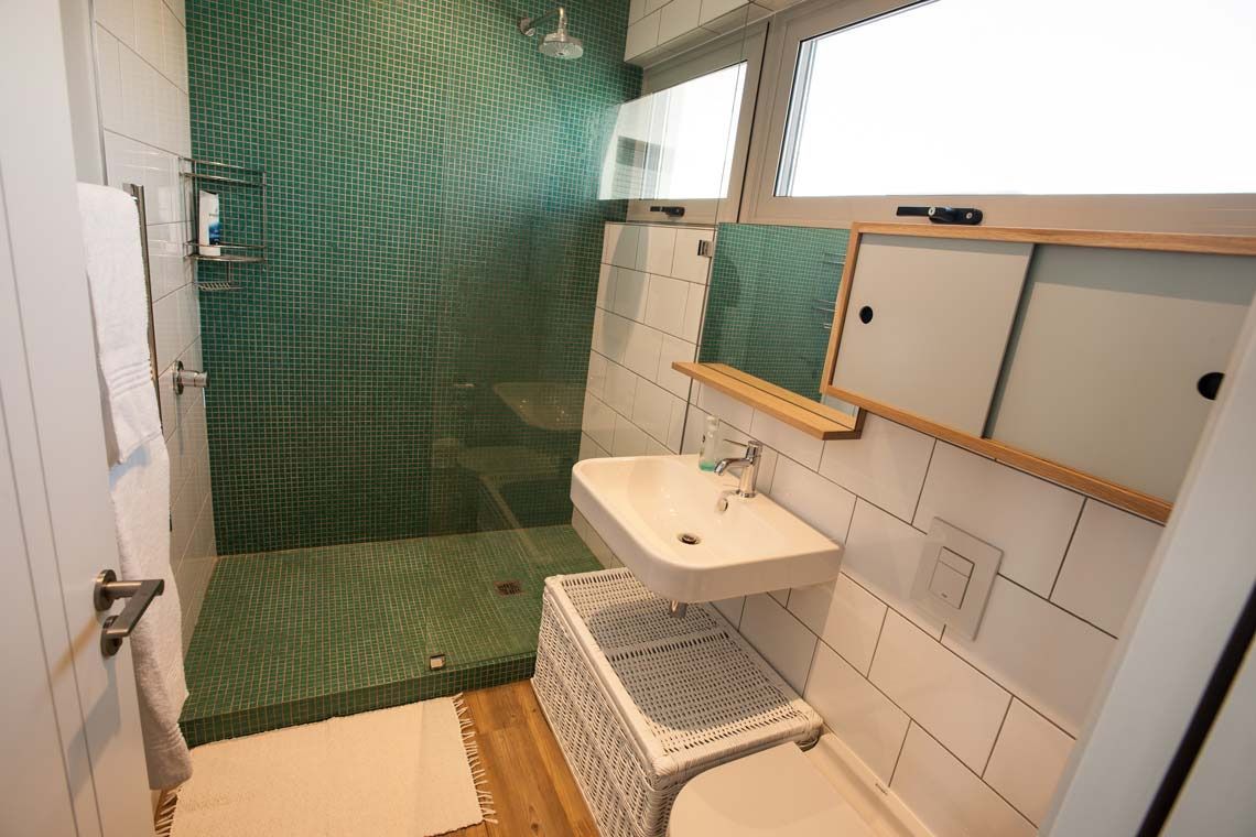 A bathroom with a shower, sink, and a small window.