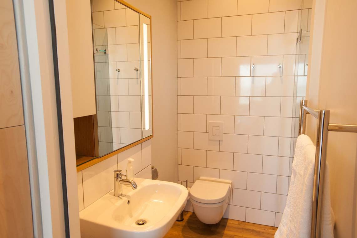 A small bathroom with a sink, toilet, and a mirror.