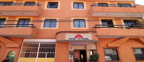 Un hotel a più piani con facciata gialla, balconi e un cartello con la scritta "HOTEL ISABEL".