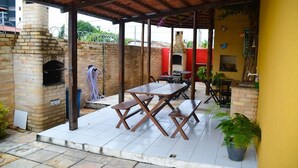Un patio al aire libre con un horno de ladrillo, mesas y sillas de madera.