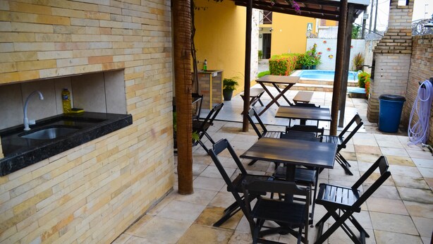 Un patio al aire libre con pared de ladrillo, un lavamanos y una mesa con sillas.