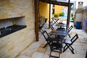 Eine Terrasse im Freien mit Backsteinmauer, Spüle und Tisch mit Stühlen.