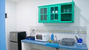 A compact kitchen with a refrigerator, microwave, sink, and a teal cabinet above the counter. - Apartamento en PlayaDelCarmen 523 by Sinbad (Playa del Carmen)