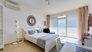 A modern bedroom with a bed, bedside lamps, a mirror, and a large window with blinds. - Villa Katarina 3 (Dubrovnik)