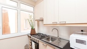 A kitchen with a gas stove, stainless steel sink, and white cabinets. - Rental In Rome Guinizzelli (Rome)