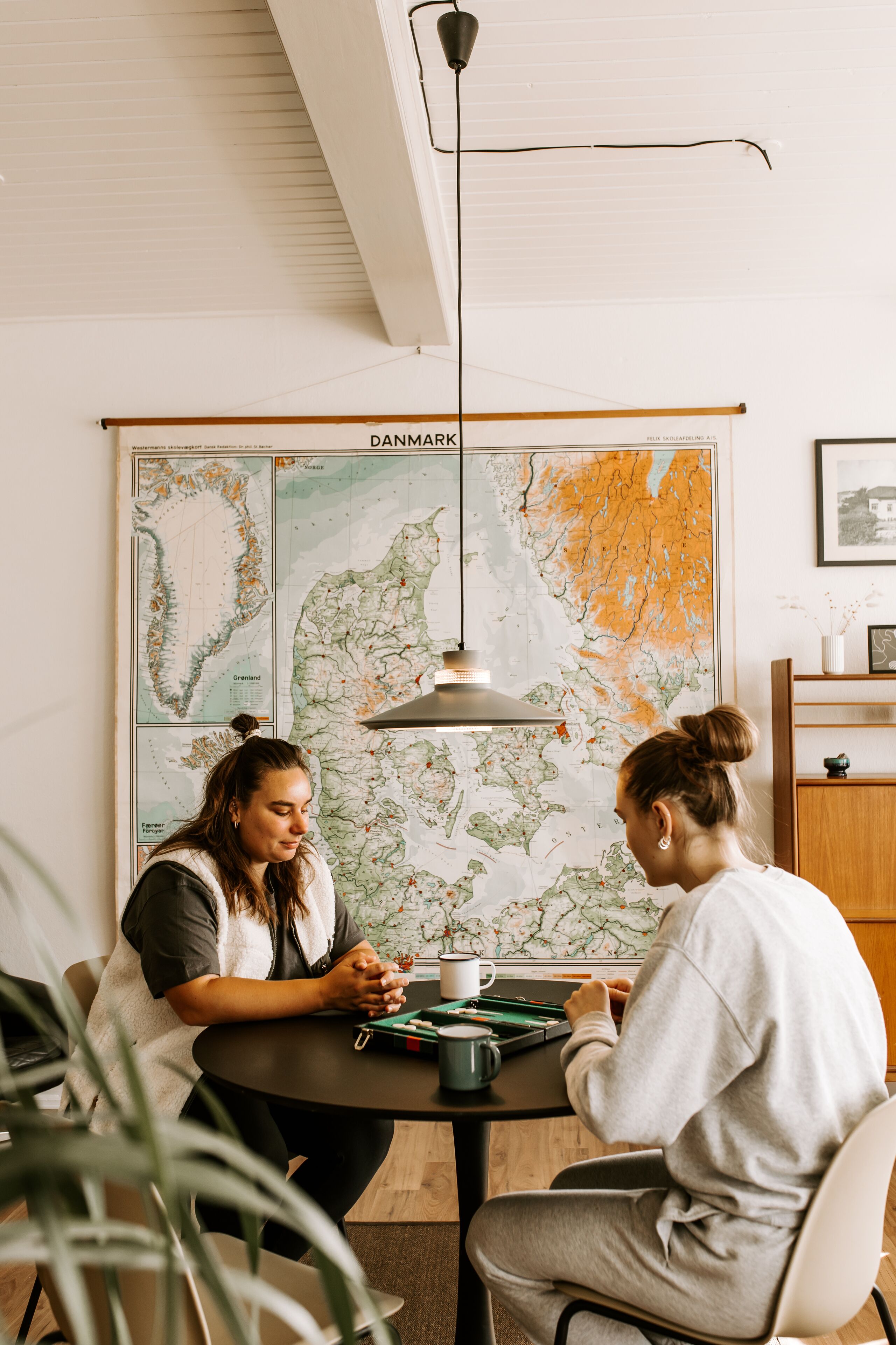 Two people sitting at a table with a map of Denmark behind them.