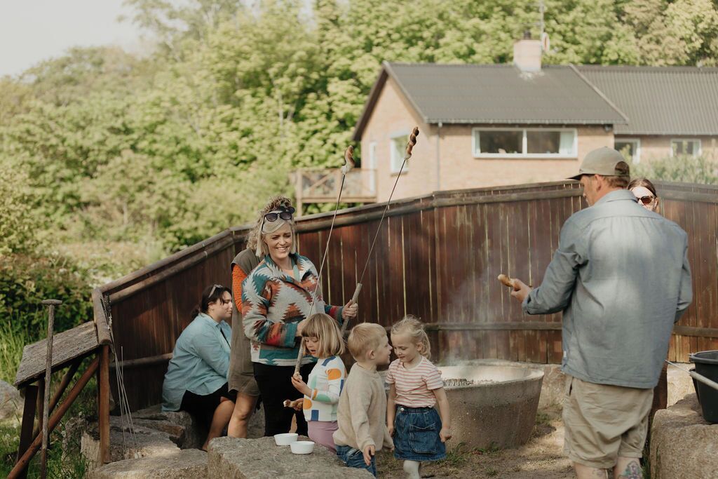 Una familia al aire libre cerca de una estructura de madera con una casa al fondo.