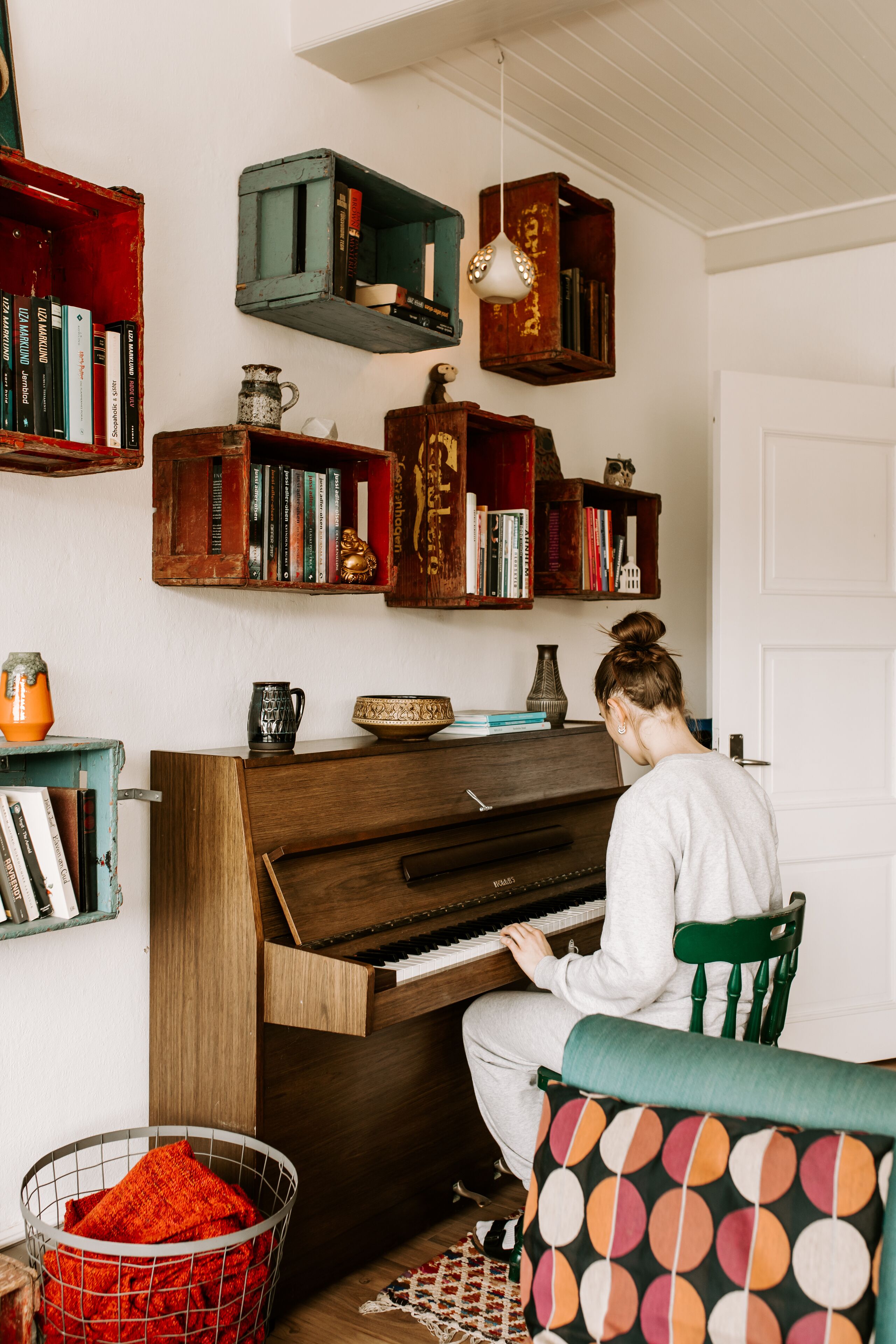 A room with a piano, bookshelves, and a person playing the piano.