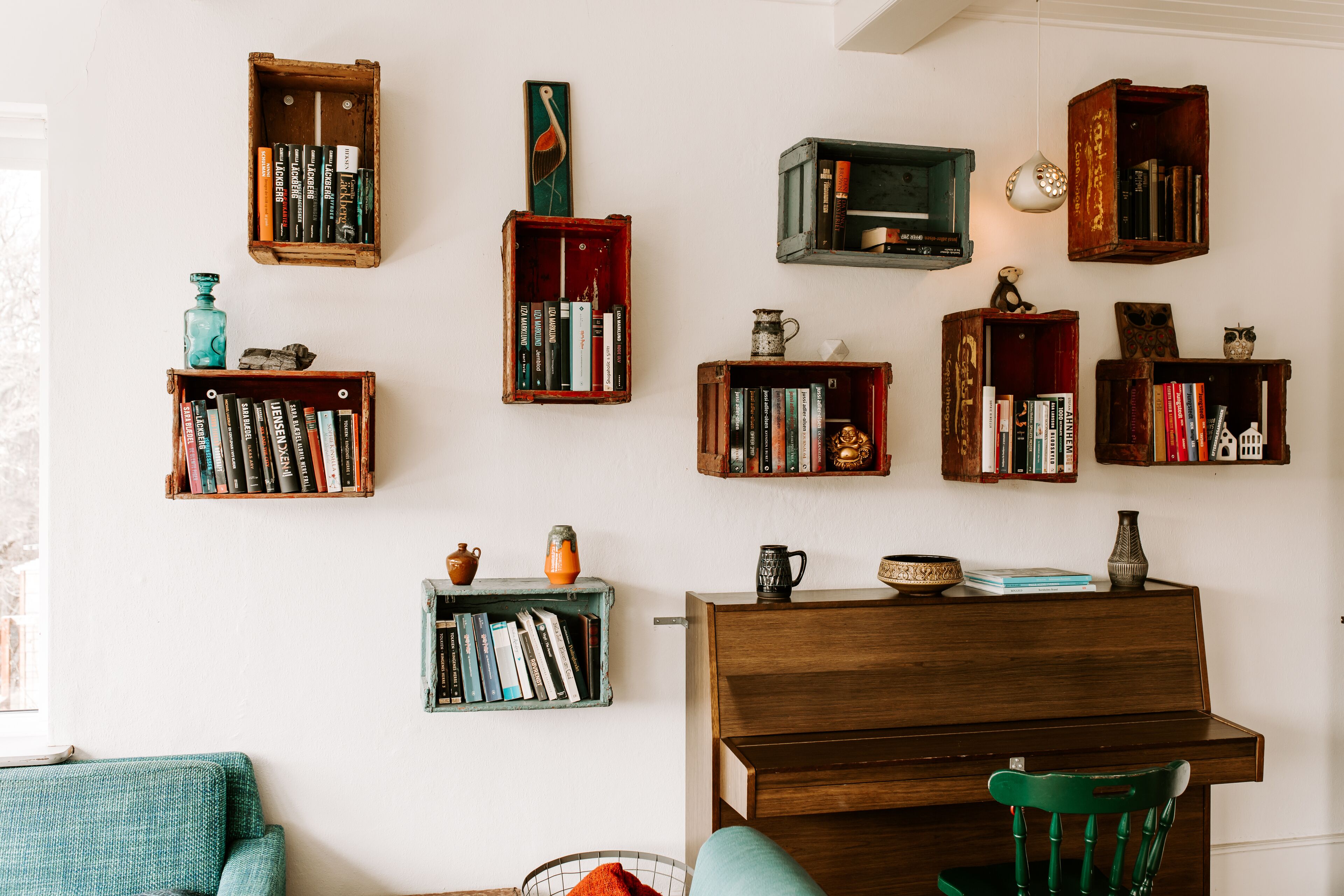 Une pièce dotée de plusieurs étagères en bois remplies de livres, d’un fauteuil vert et d’un piano en bois.
