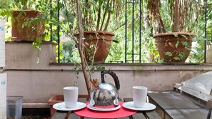 A table with a teapot and two cups, surrounded by potted plants and a window with a view of greenery. - Rental In Rome Riari Loft (Rome)