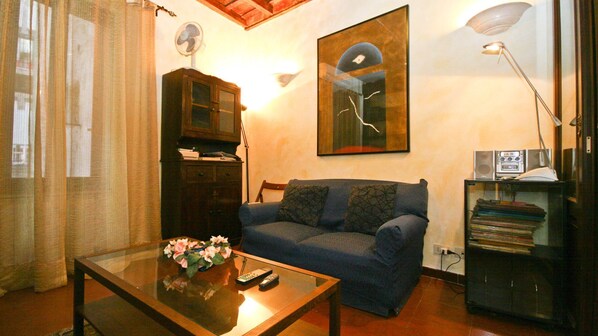 A living room with a sofa, a coffee table with a vase, a cabinet, a lamp, and a wall-mounted picture.