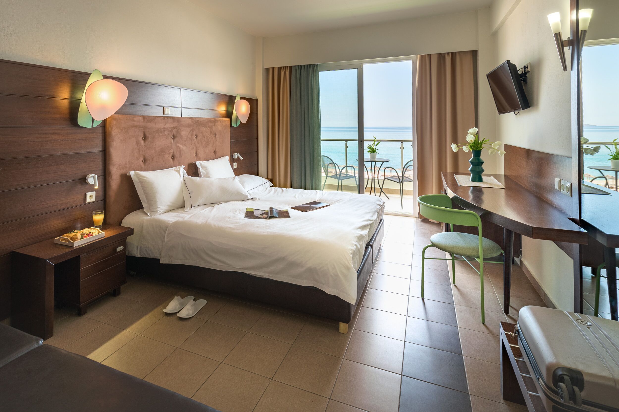 Ein Hotelzimmer mit Bett, Nachttisch und Meerblick.
