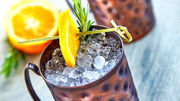 Two copper mugs with ice and garnishes on a wooden surface.