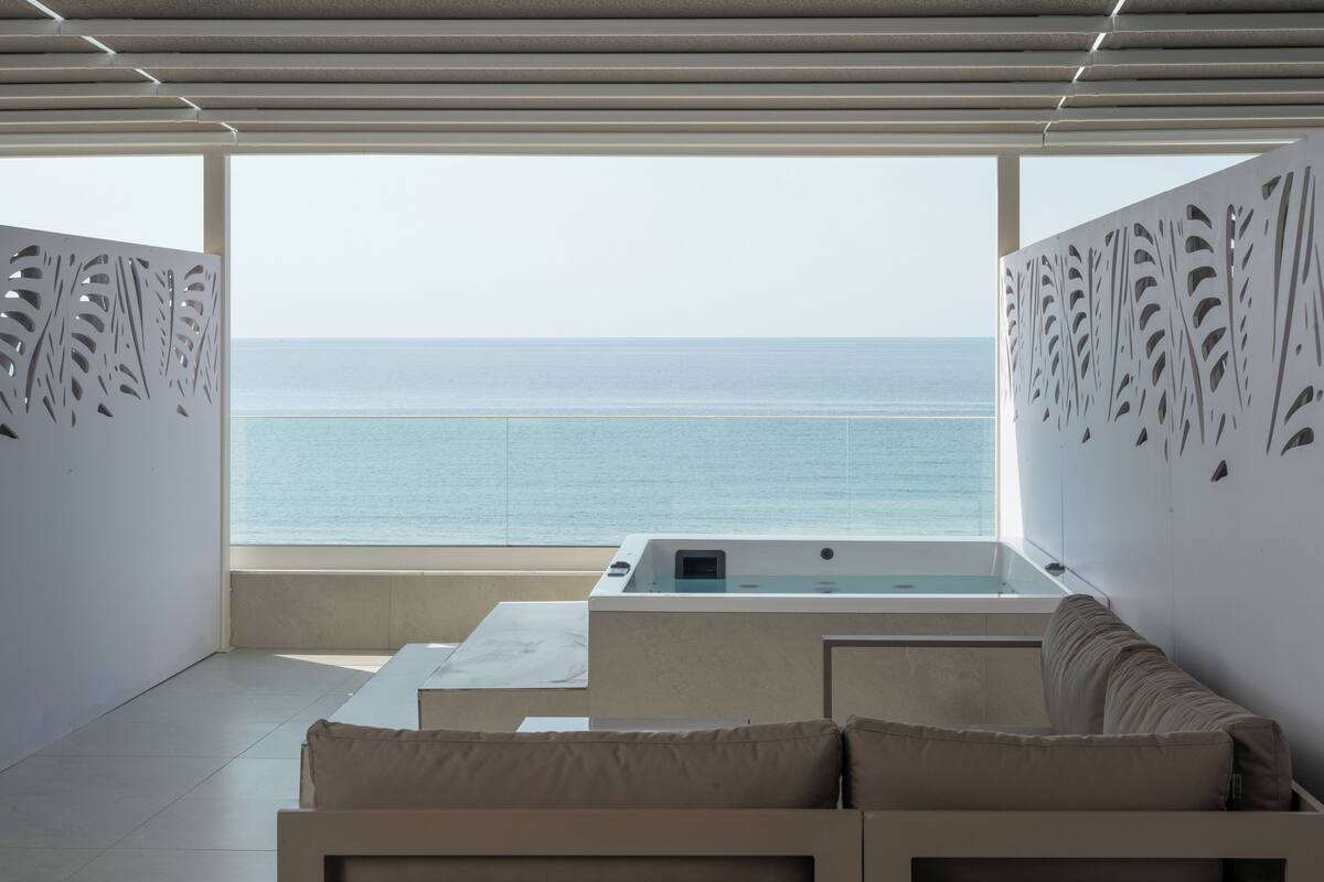 Quarto moderno com vista para o mar, uma banheira e um sofá.
