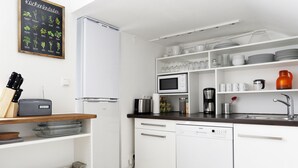 A modern kitchen with white cabinets, a microwave, and a dishwasher. There is a wooden shelf with kitchen utensils and a knife block. - DROY Droysenstr. Old building - box spring beds - near Kurfürstendamm (Berlin)