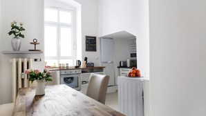 A modern kitchen with white appliances, a wooden dining table, and a vase with flowers. - DROY Droysenstr. Old building - box spring beds - near Kurfürstendamm (Berlin)