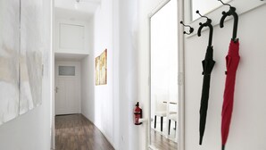 A hallway with a white door, a fire extinguisher, and two umbrellas hanging on hooks. - DROY Droysenstr. Old building - box spring beds - near Kurfürstendamm (Berlin)