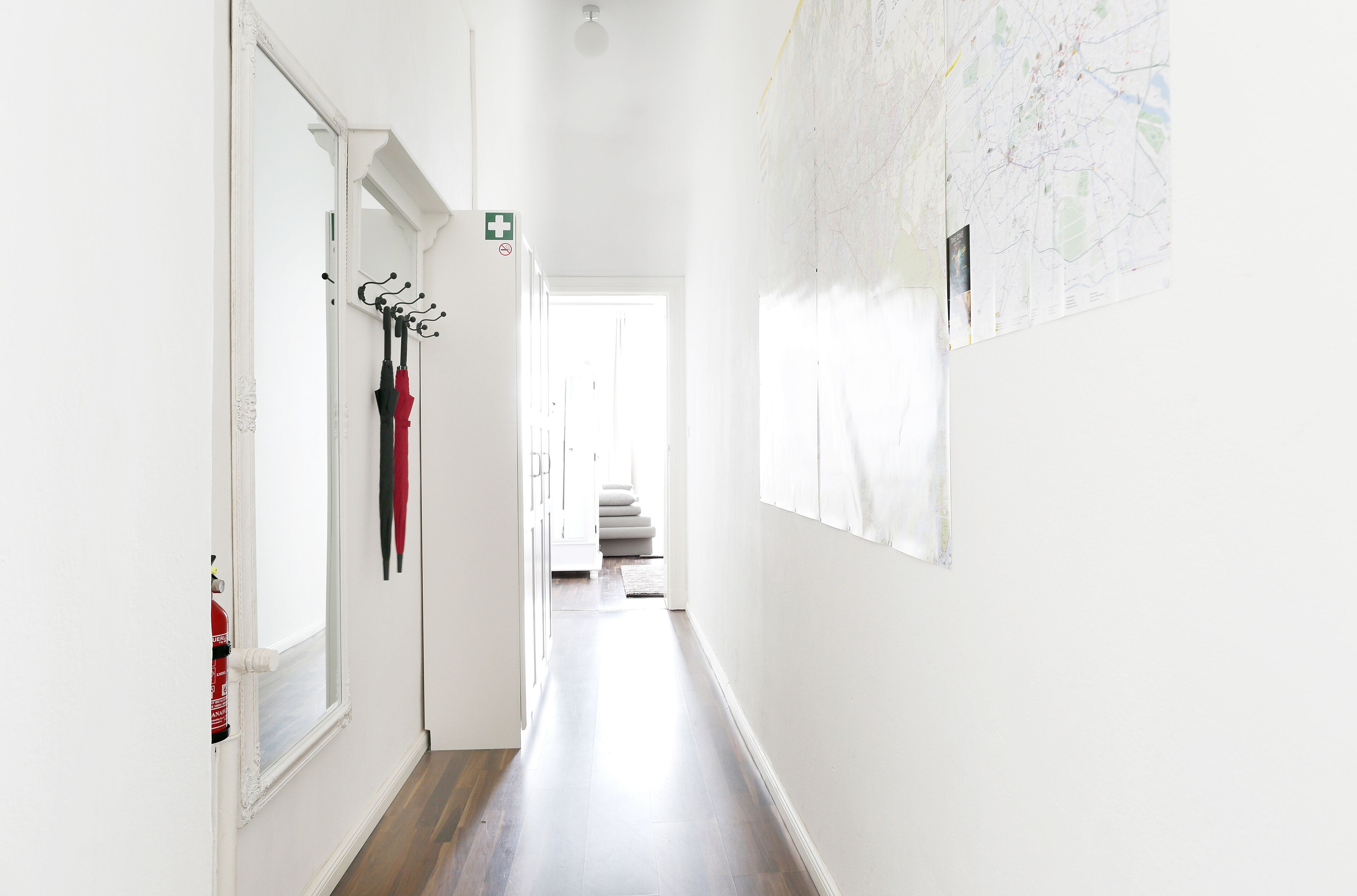 A hallway with white walls, a wooden floor, and a map on the wall.