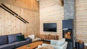 Uma sala de estar moderna com parede de madeira, lareira, televisão de tela plana e sofá.