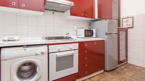 Una cocina compacta equipada con lavadora, microondas, refrigerador y estufa a gas.