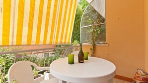 A balcony with a white table, two green chairs, a bottle, and a bag of snacks. - Rental In Rome Pateras Flower (Rome)