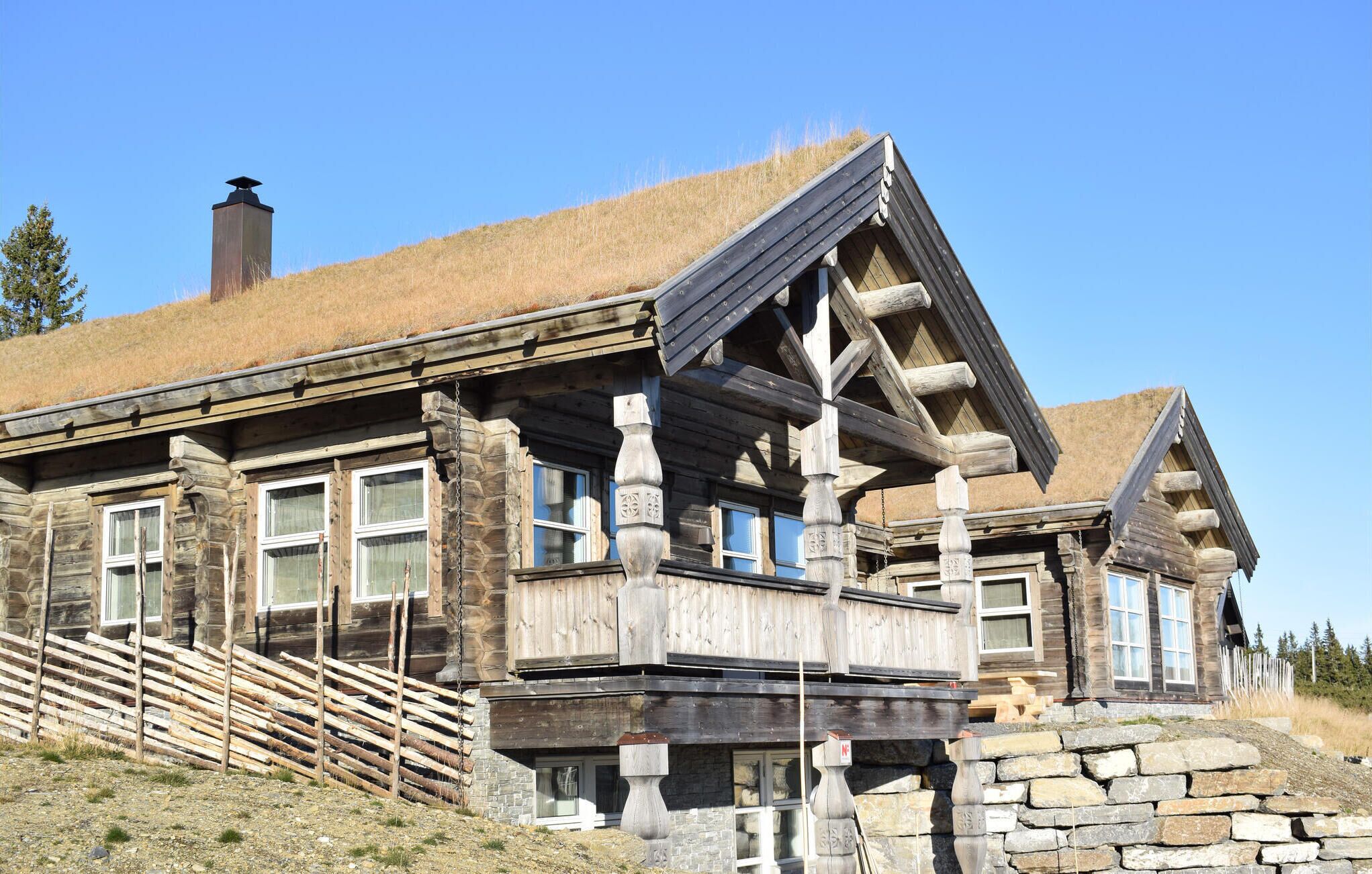 A log cabin with a stone foundation, large windows, and a sloped roof.
