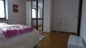 A bedroom with a bed, a wardrobe, a radiator, and a small table.