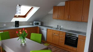A modern kitchen with wooden cabinets, a dishwasher, an oven, and a skylight.