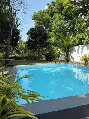 A rectangular swimming pool with a tiled edge, surrounded by lush greenery and trees. - Peaceful, private self contained villa. Just a few steps from the beach! (Tangalle)