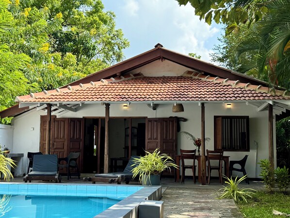 A house with a tiled roof, a swimming pool, and outdoor furniture. - Peaceful, private self contained villa. Just a few steps from the beach! (Tangalle)