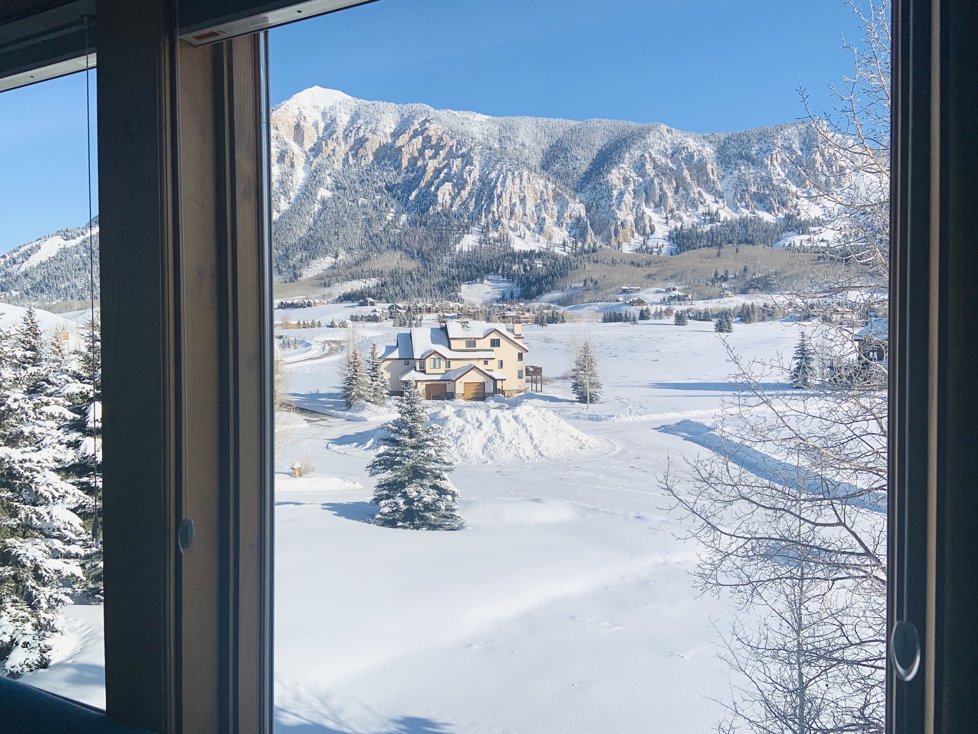A snow-covered landscape with a house and mountains in the background.