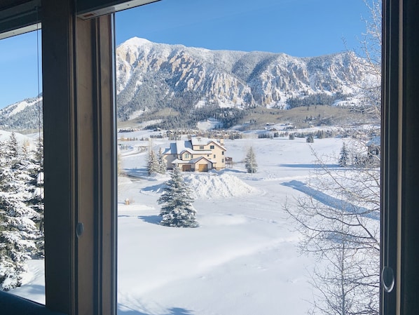 Paisaje nevado con una casa y montañas al fondo.