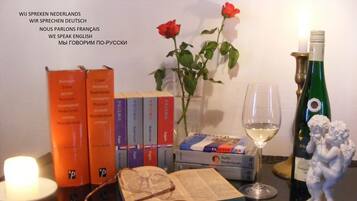 A table with books, a candle, a glass of wine, and a statue.