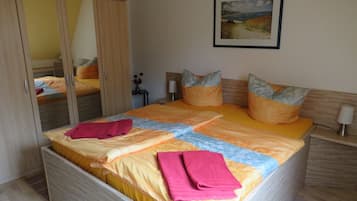 Een slaapkamer met een bed, een kledingkast, een nachtkastje en een schilderij aan de muur.