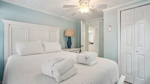A bedroom with a bed, white headboard, ceiling fan, and a door. - Short Walk to Shops, Restaurants & Beach Access,Pet Friendly, Private fenced in yard (Folly Beach)