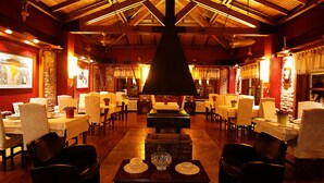 Un restaurante acogedor con vigas de madera, mesas con sillas y una pieza decorativa central.