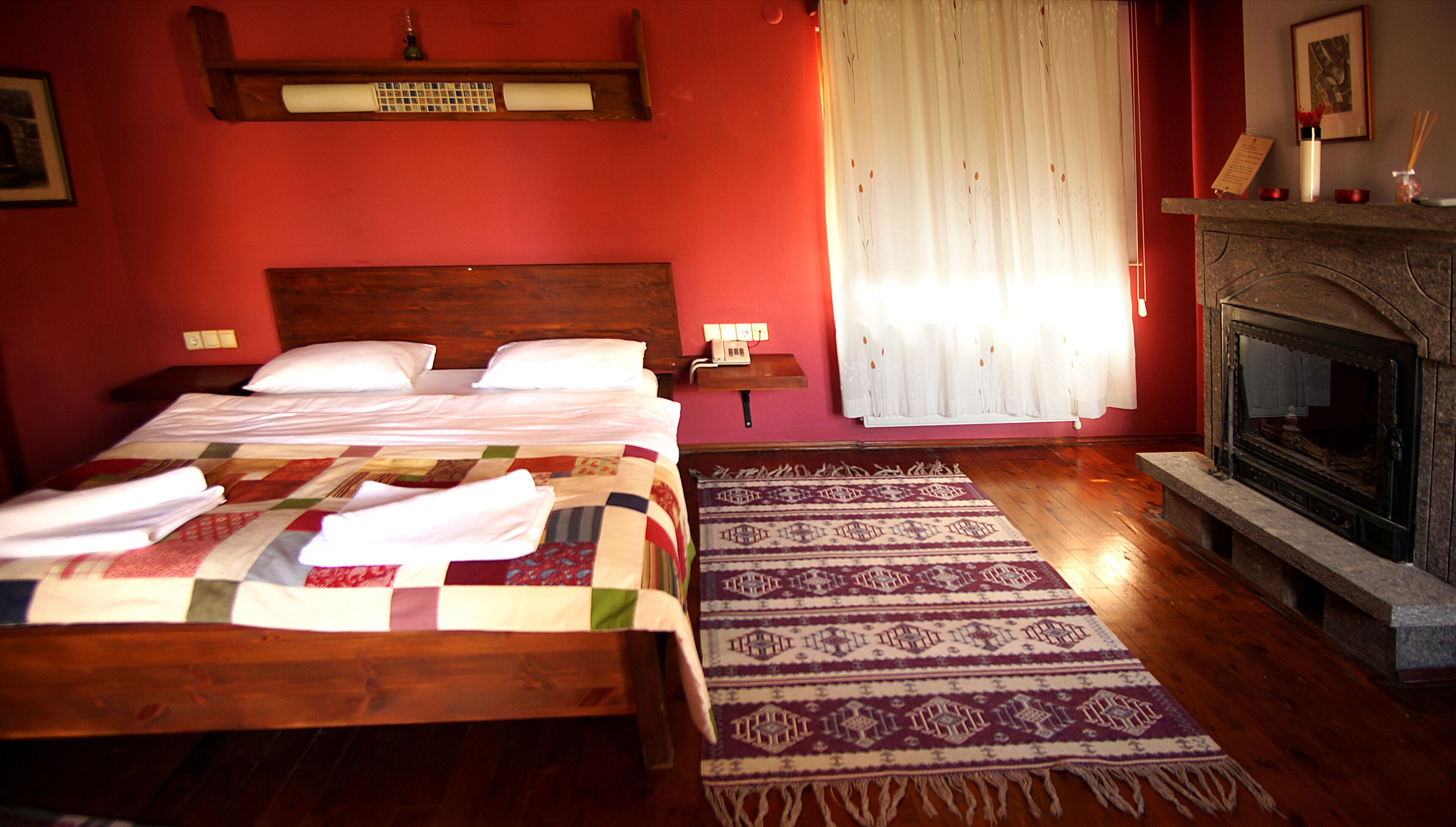 Una habitación de hotel con dos camas, una chimenea y una pared roja.