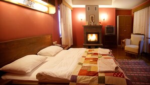 Una habitación de hotel con una cama, chimenea, televisor y una silla.